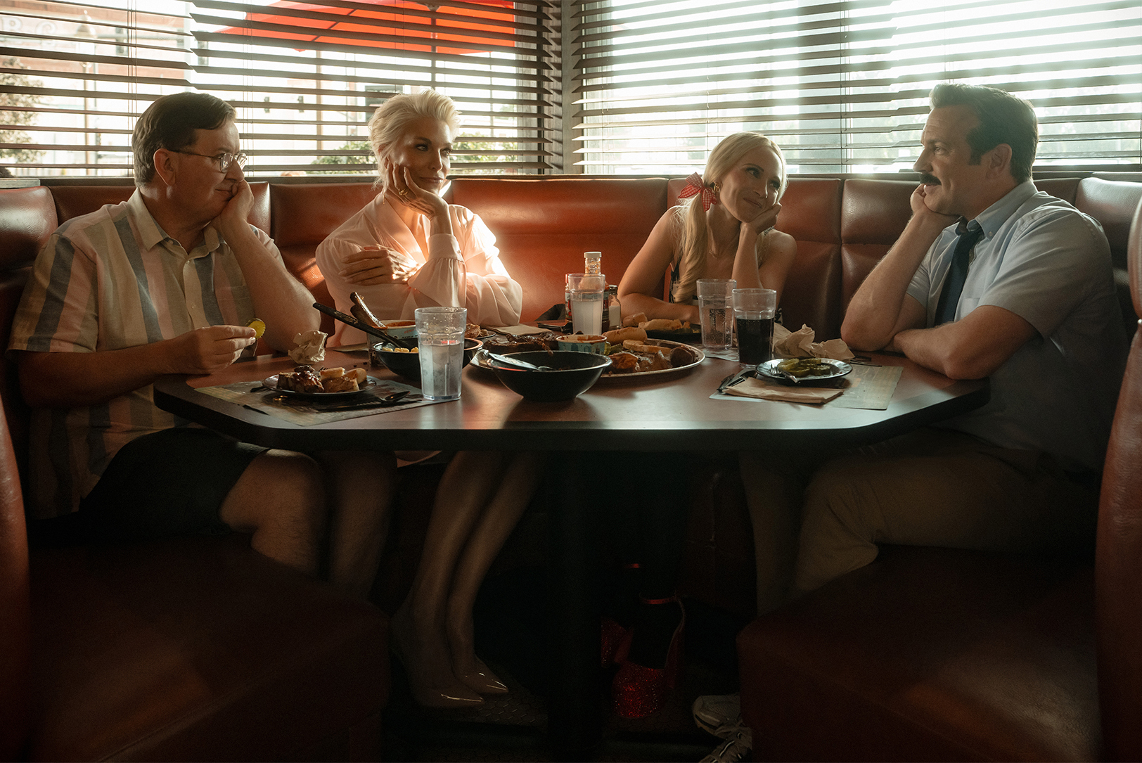 Actors Jeremy Swift, Hannah Waddingham, Juno Temple and Jason Sudeikis are shown in a promotional photo for "Ted Lasso," shot inside Gates BBQ in Kansas City; photo courtesy of Apple TV+