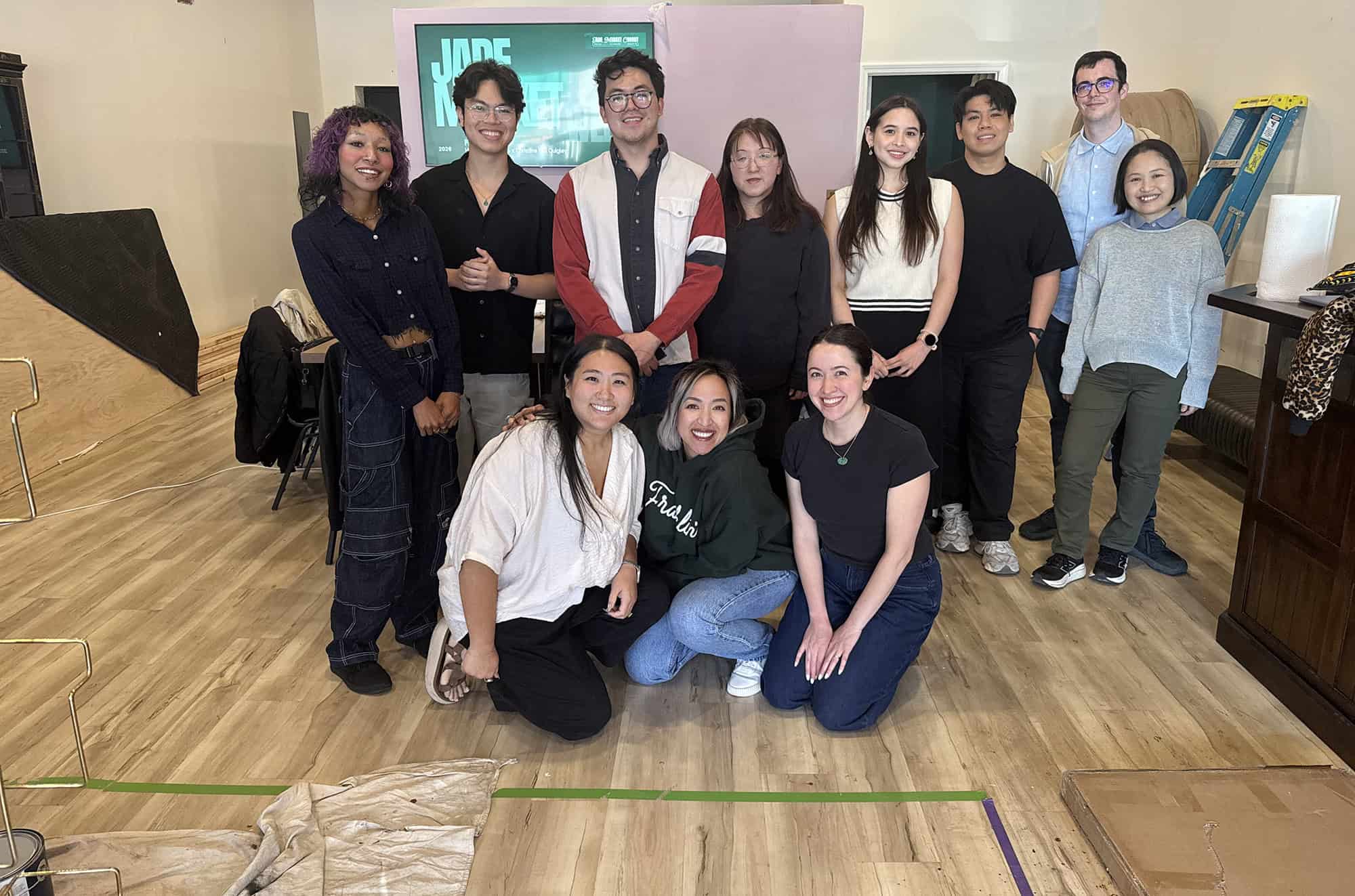 Members of the inaugural Jade Market Cohort pose with the program's leaders amid paint cans and construction materials in the new headquarters for Hella Good Deeds; courtesy photo