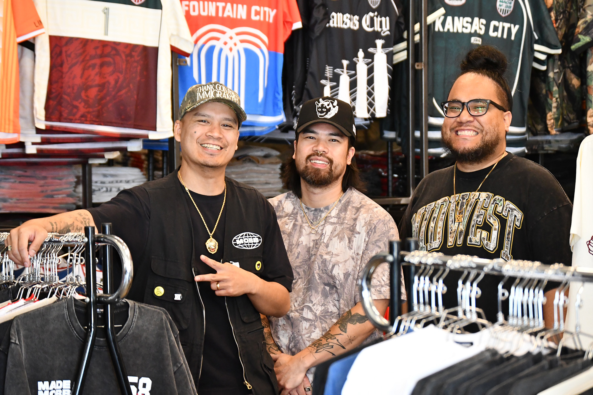 Jesse Phouangphet, Vu Radley, and Mark Launiu, co-founders of MADE MOBB, stand in front of a wall of jerseys inspired by Kansas City and teams playing in the 2026 FIFA World Cup; photo by Tommy Felts, Startland News