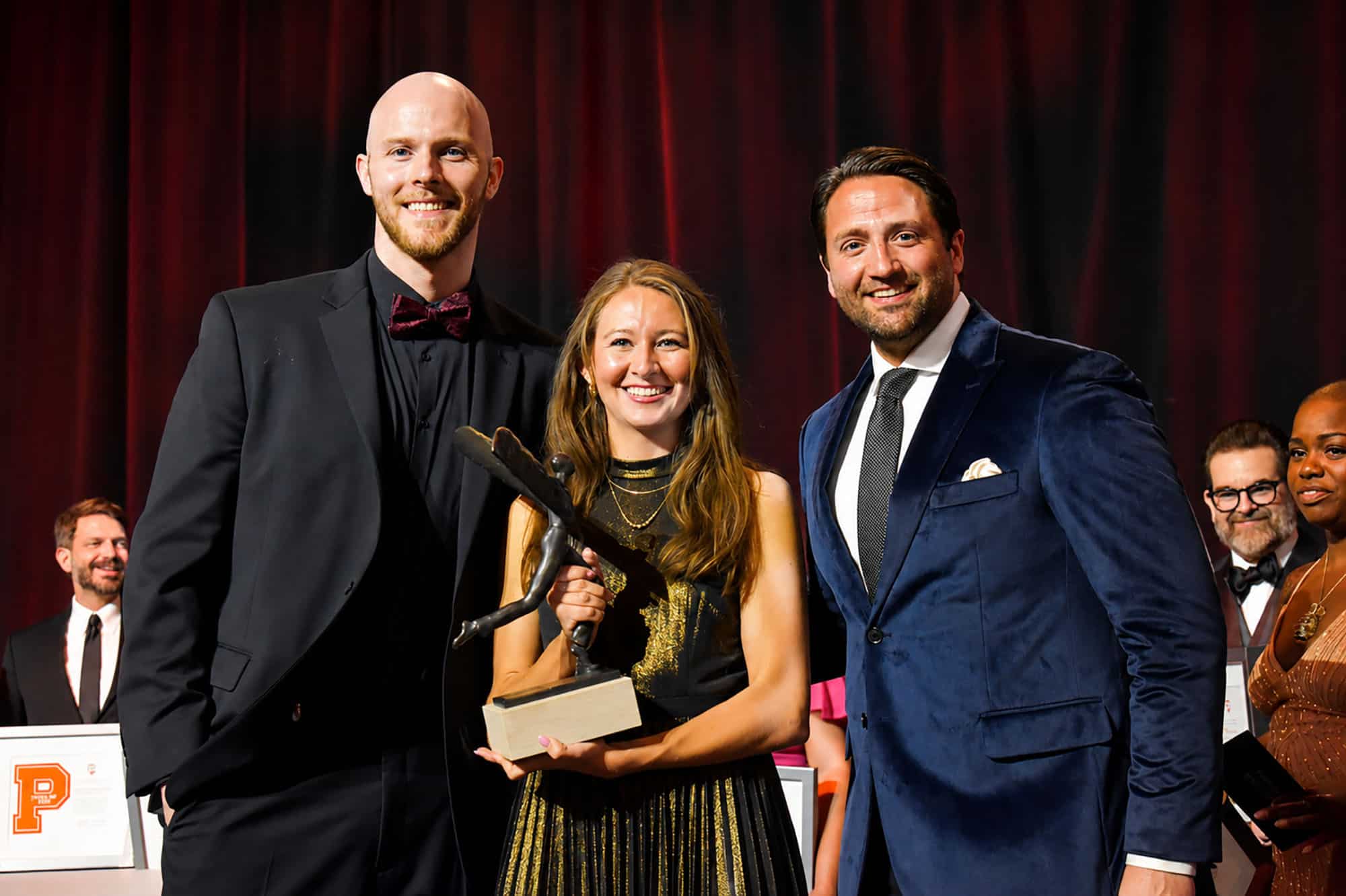 Kalin Baca, founder of Icorium Engineering Company, center, takes the stage after accepting the 2025 Innovator of the Year Award from Parker Graham, Finotta founder and Innovator of the Year for 2021, and Taylor Stormberg, Pando PEO, the winner for 2024; photo by Nikki Overfelt Chifalu, Startland News