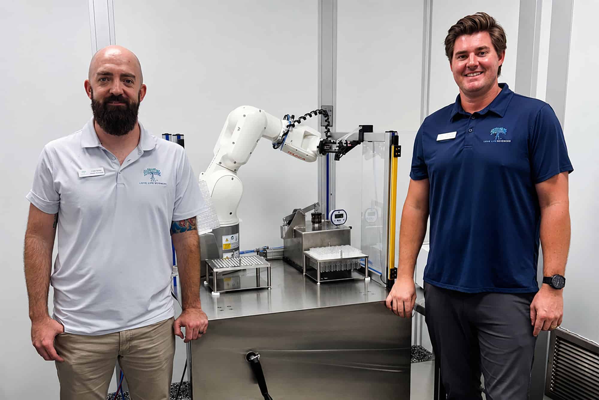 Colby Spiess, regulatory and quality specialist with Love Lifesciences, and Bradley Hopper, CTO and co-founder, stand with the life science company's robotic fill-finish system; courtesy photo