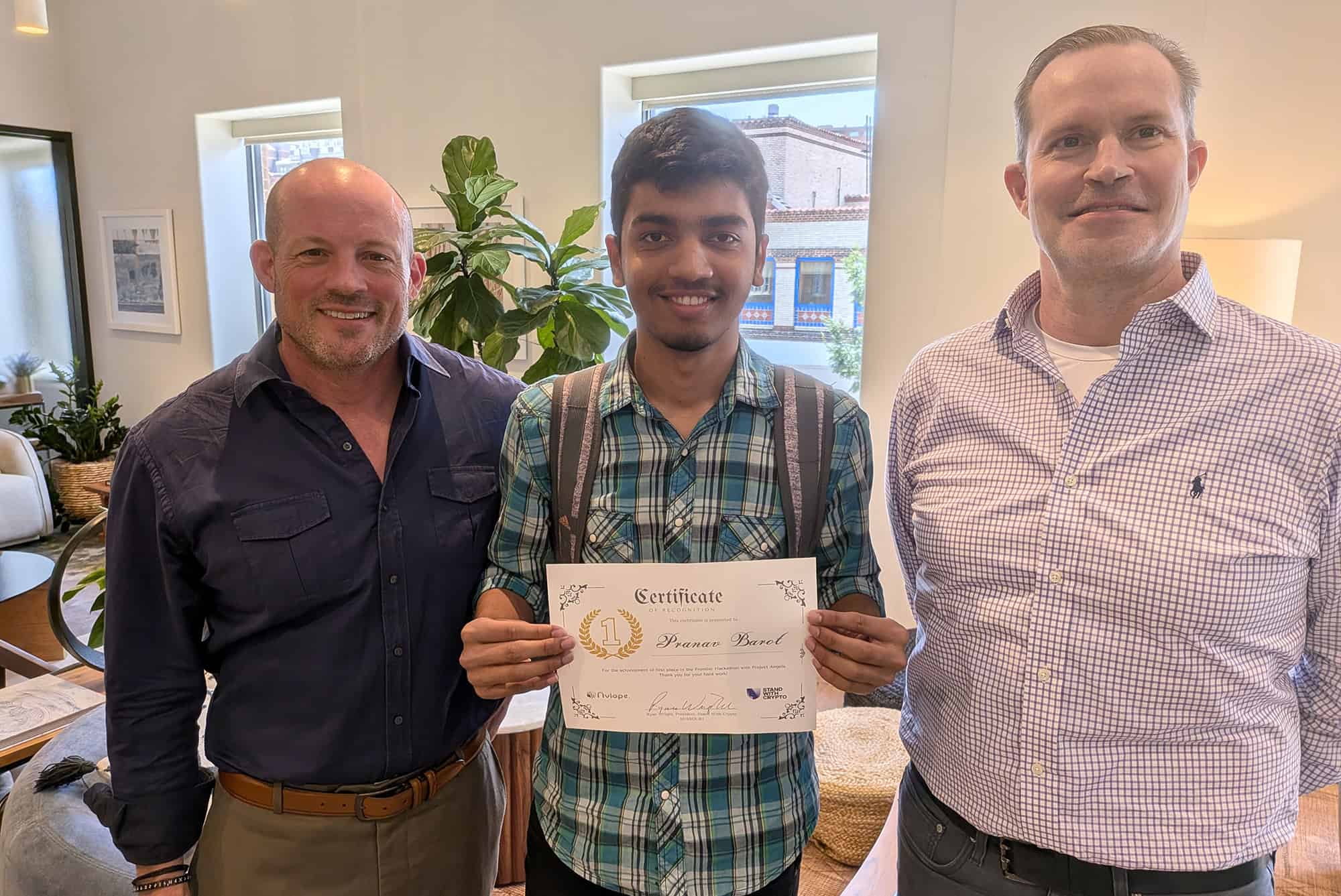 Pranav Barot, Aegis, center, is awarded first prize in Kansas City's Frontier Technology Hackathon by competition judge Tom Flynn, core Contributor at Apex Fusion and Coherence, and COO of HAL8; and Ryan Wright, president of Stand With Crypto Missouri and a MOMENT organizer; courtesy photo