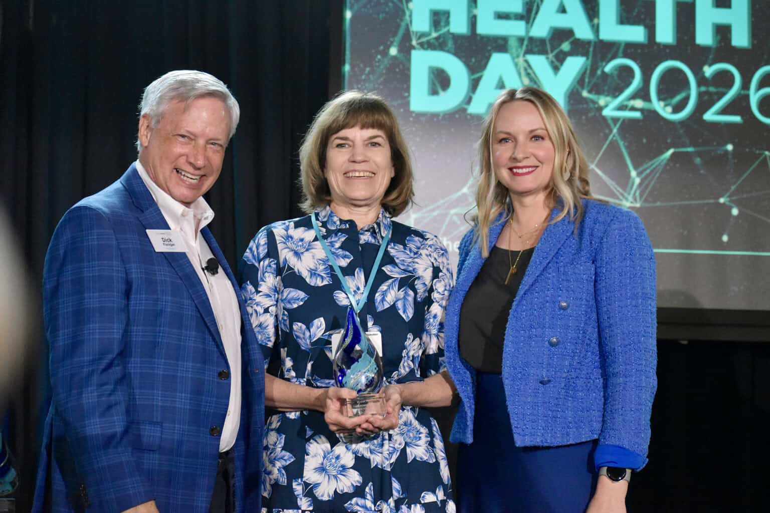 Maria Meyers, vice chancellor of commercialization and entrepreneurship at the University of Missouri-Kansas City, center, accepts the Lumi Award for Impact and Influence at Digital Health Day from Dick Flanigan, president of Digital Health KC, and Elizabeth Shaffer, program director for Digital Health KC; photo by Nikki Overfelt Chifalu, Startland News