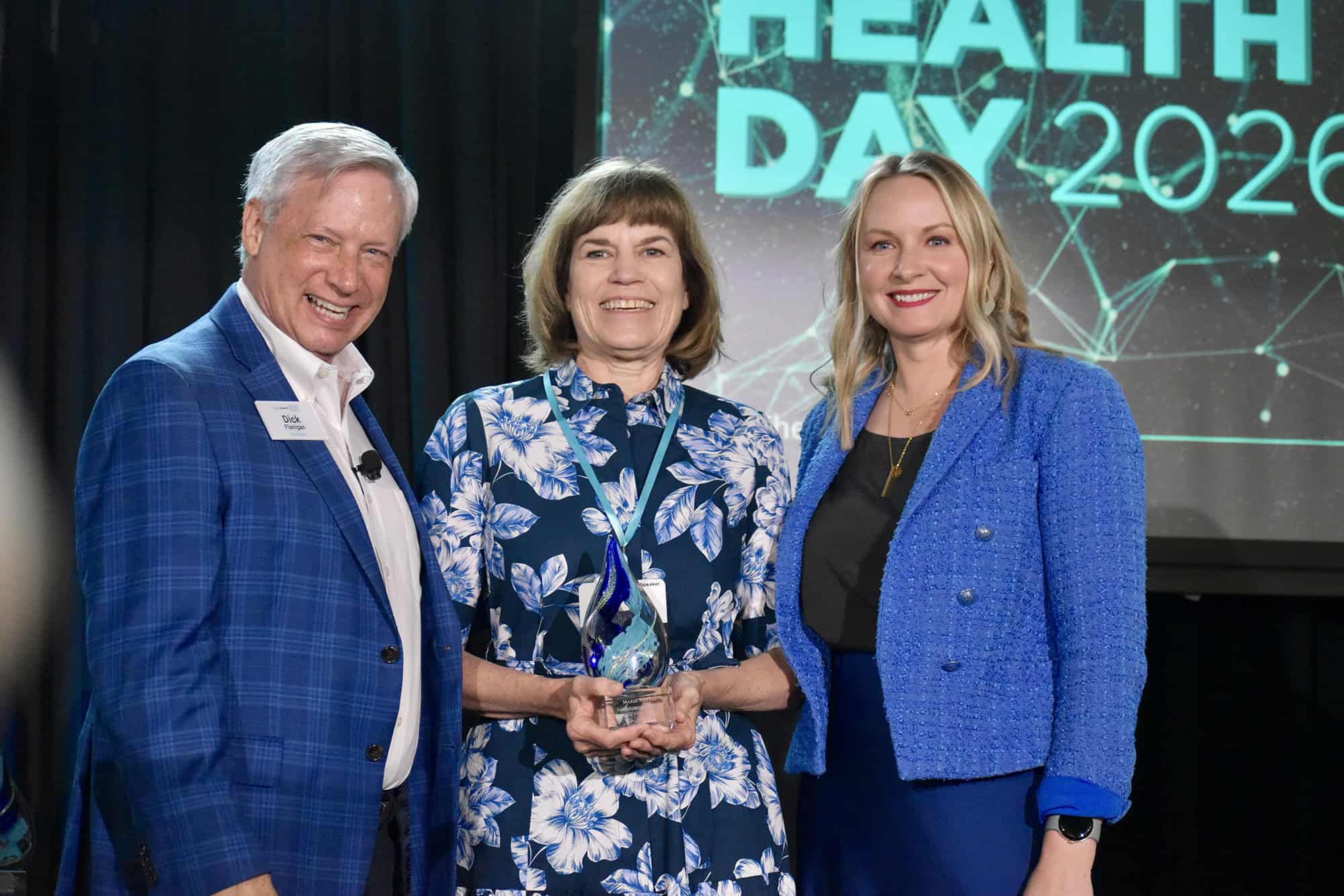 Maria Meyers, vice chancellor of commercialization and entrepreneurship at the University of Missouri-Kansas City, center, accepts the Lumi Award for Impact and Influence at Digital Health Day from Dick Flanigan, president of Digital Health KC, and Elizabeth Shaffer, program director for Digital Health KC; photo by Nikki Overfelt Chifalu, Startland News
