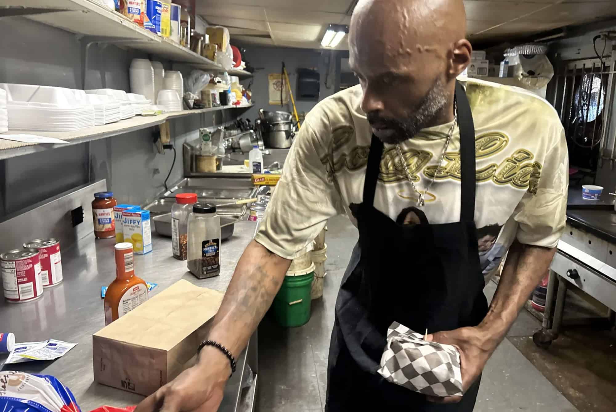 Eddie Scover, son or Ruth Scover, founder of Ms. R's Cafe, packs cheeseburgers for a to-go lunch order. The elder Ms. Scover passed away in 2021, and Eddie now runs the cafe; photo by Brandon Azim, KCUR