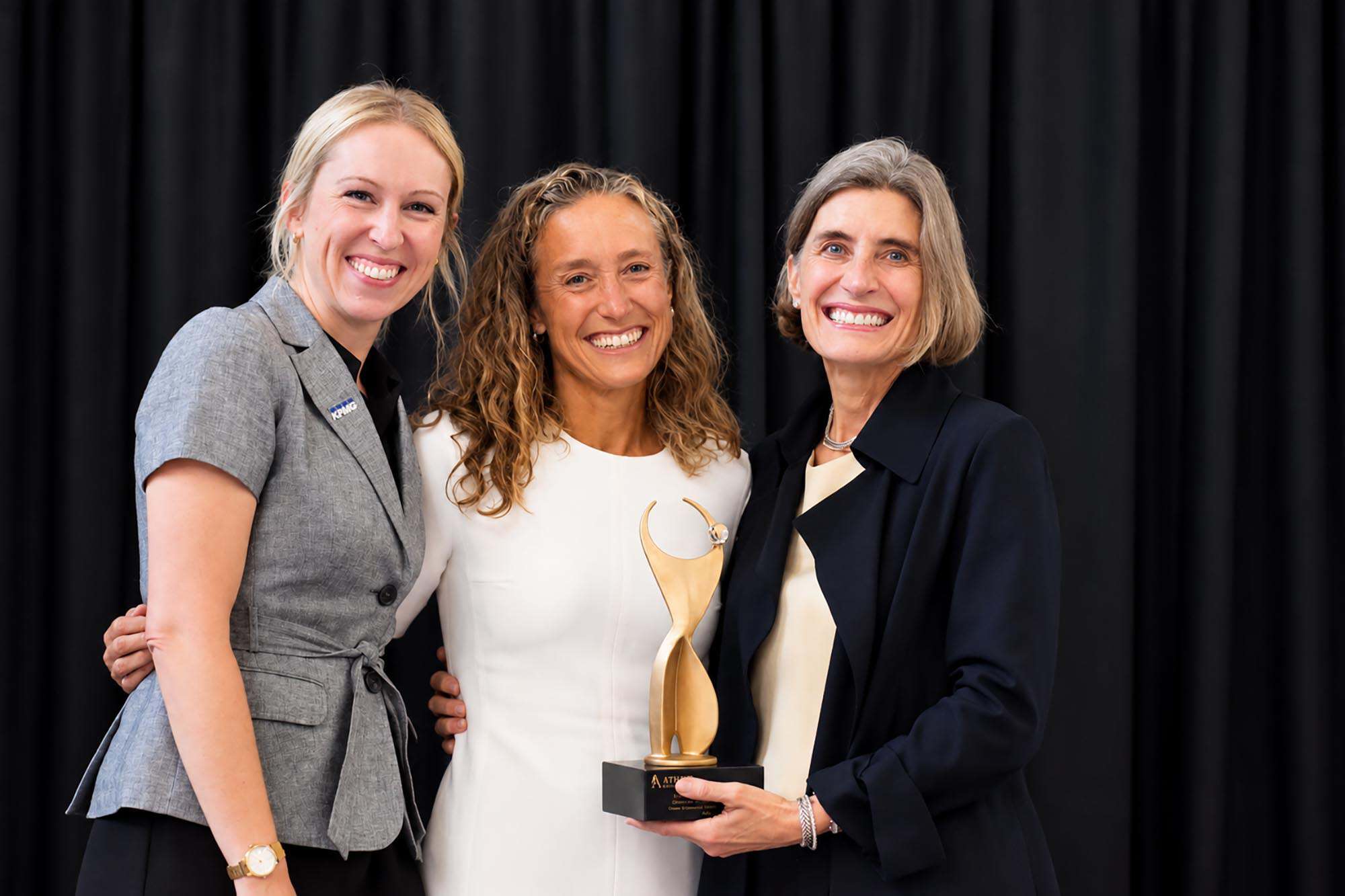 Jenny Pearson, KPMG; Angie Long, Kansas City Current and Palmer Square Capital Management; and Christine Kemper, Kansas City Girls Preparatory Academy, stand together on stage after Long was honored with the 2026 ATHENA Leadership Award; photo by Nikki Overfelt Chifalu, Startland News