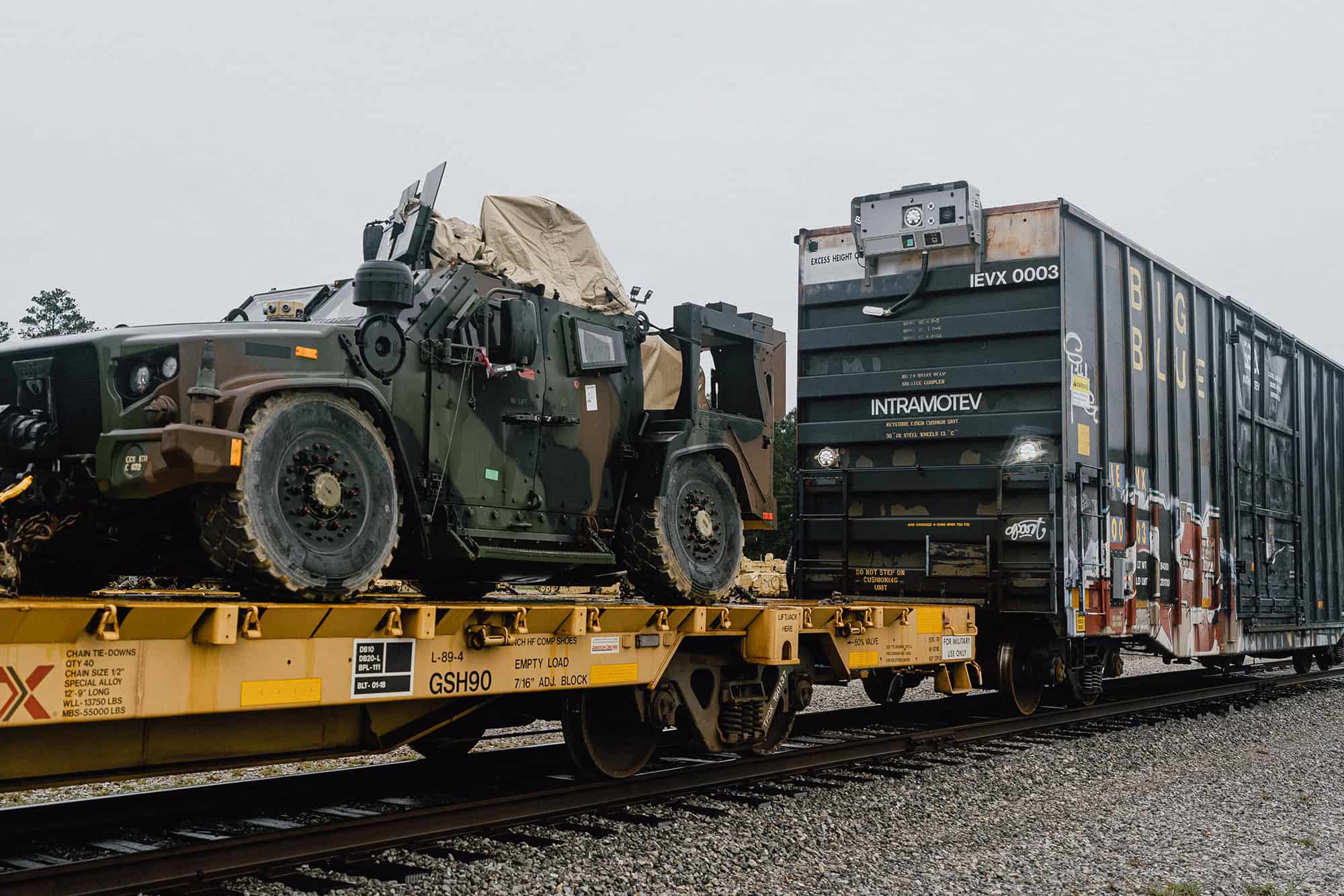 A TugVolt-equipped autonomous railcar hauls an Army truck on a flatcar in June at Camp Shelby, Mississippi; photo courtesy of Intramotev