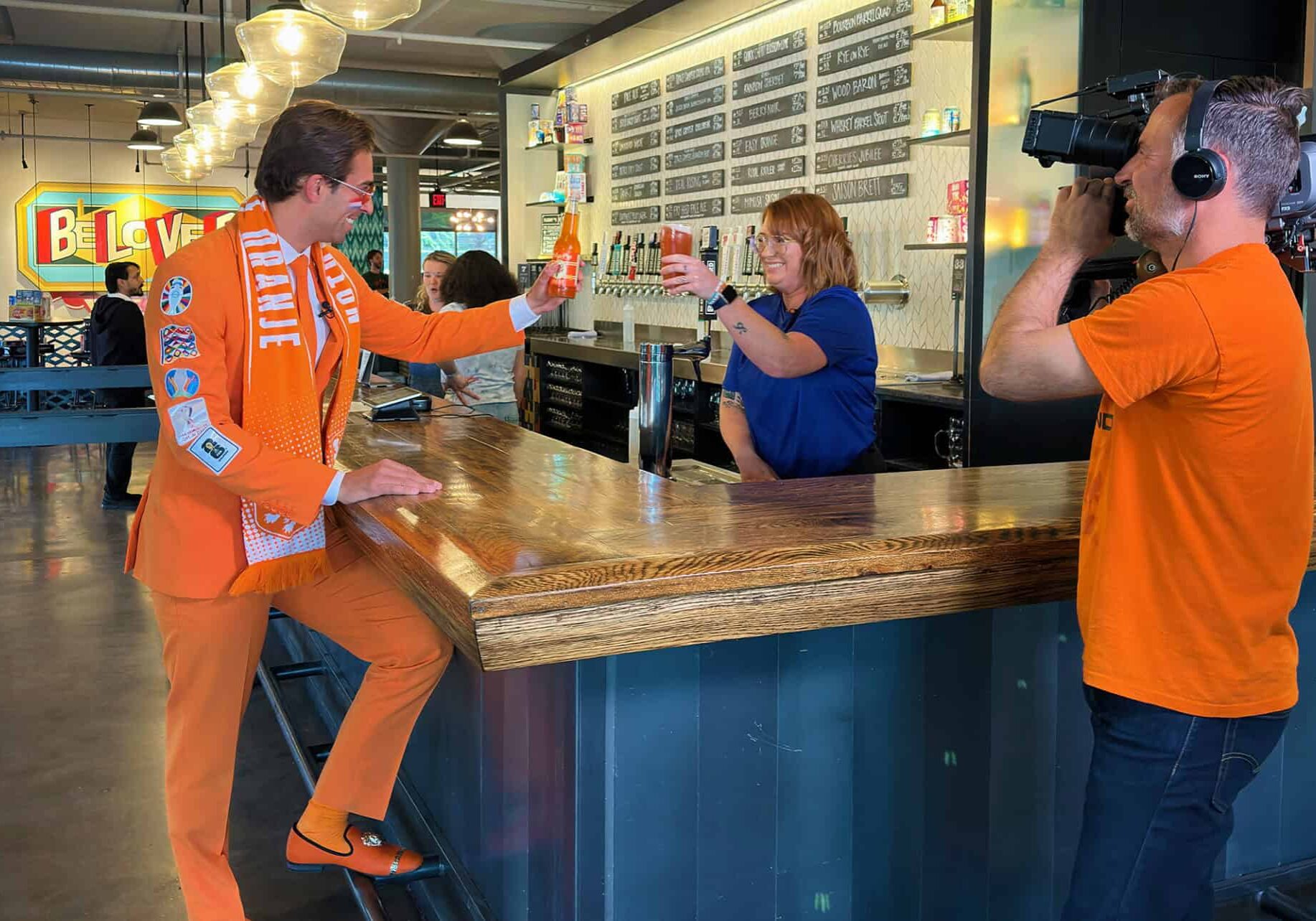 Daniel Oordt, The Oranje Suit Man, shares a cheers with members of the Boulevard team during filming at the Boulevard Tours & Rec Center in Kansas City; photo by Joyce Smith